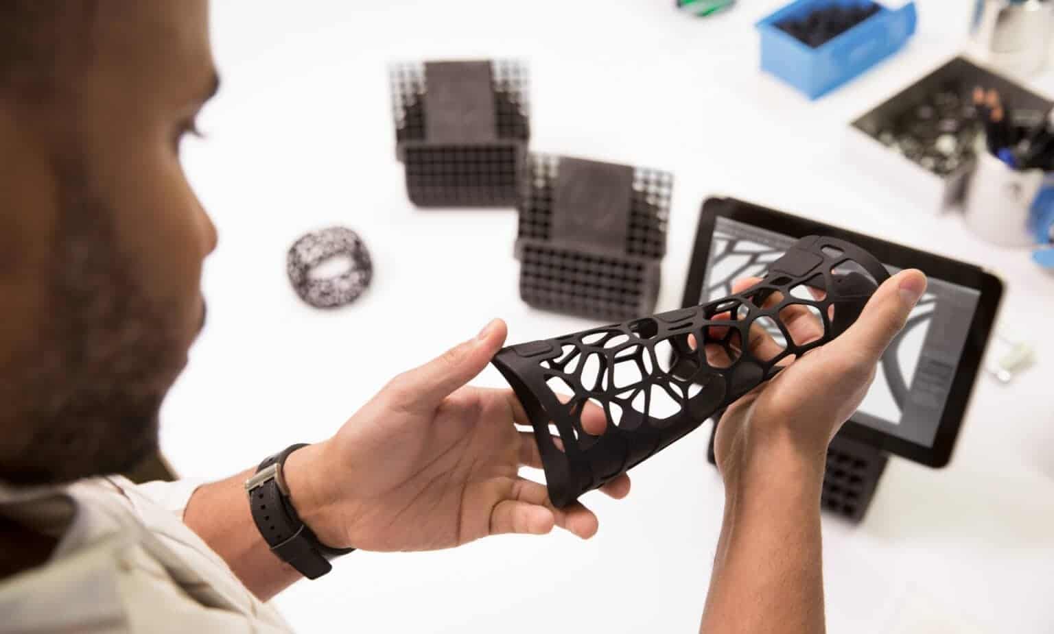 Engineer holding a 3D printed hand prototype, demonstrating manufacturing processes for engineering materials during a design review.